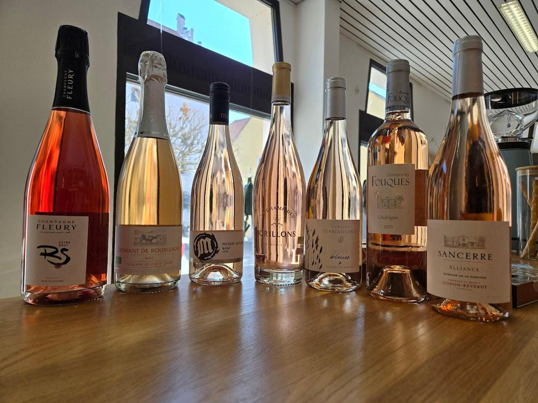 Verschiedene Roséwein- und Champagnerflaschen auf Holztisch vor Fenster, Weinprobe