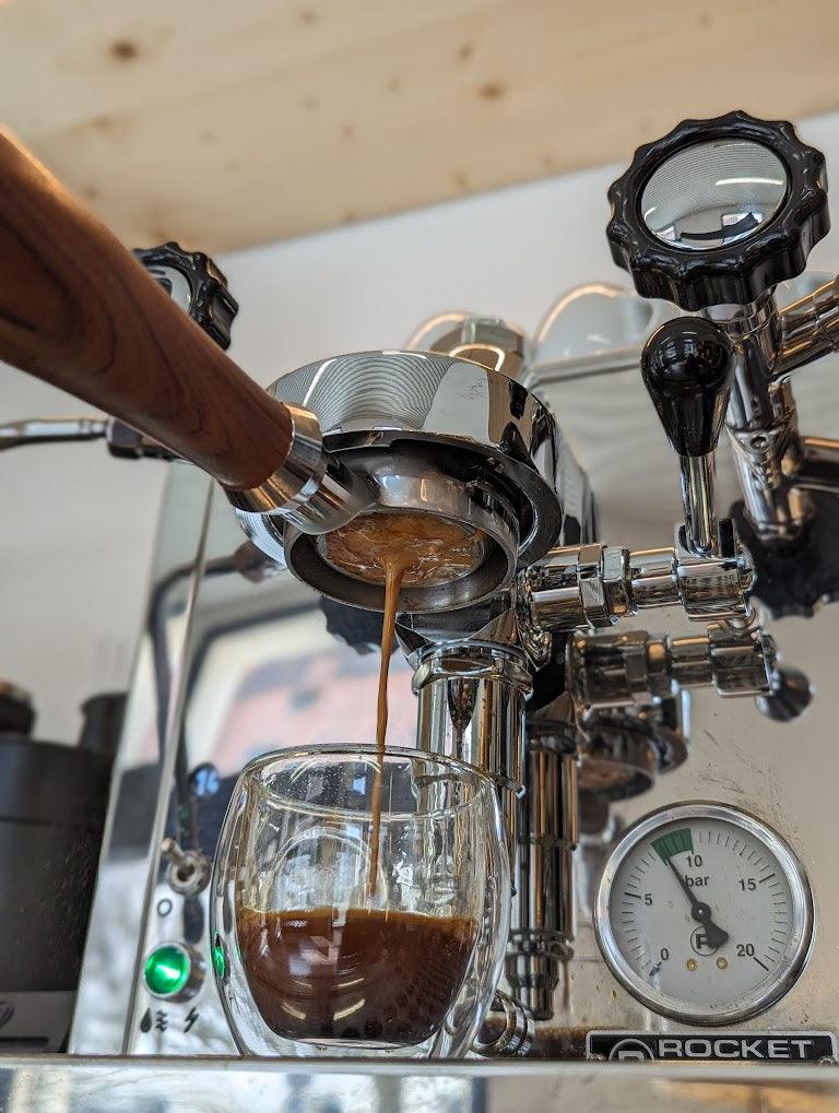 Espresso läuft aus Siebträgermaschine in Glas, Rocket Espressomaschine, Nahaufnahme