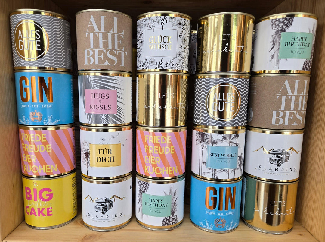 Verschiedene bunte Kuchen-Dosen mit Geburtstags- und Glückwunschmotiven im Regal